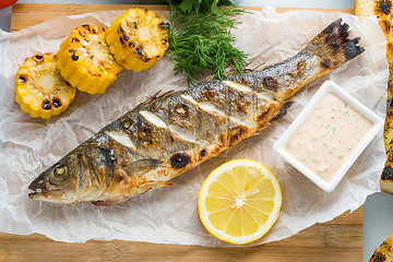 Image showing fish baked on the grill. with potatoes and lemon. 