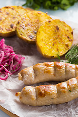 Image showing macro meat kupaty with fries and greens on white plate