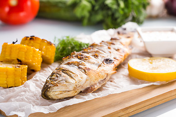 Image showing fish baked on the grill. with potatoes and lemon. 