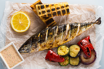 Image showing fish baked on the grill. with potatoes and lemon. 