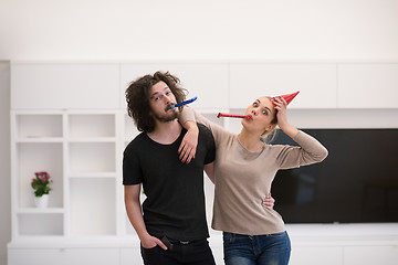 Image showing couple in party hats blowing in whistle