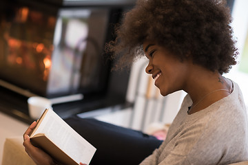 Image showing black woman reading book  in front of fireplace