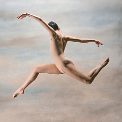 Image showing Young beautiful modern style dancer jumping on a studio background