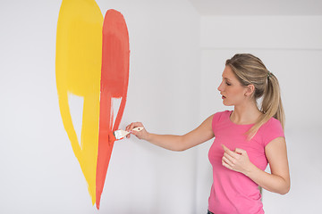 Image showing woman painting a heart on the wall