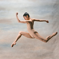 Image showing Young beautiful modern style dancer jumping on a studio background