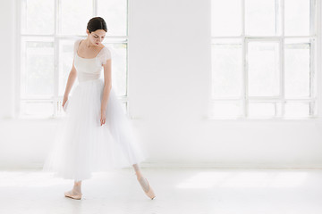 Image showing Young and incredibly beautiful ballerina is posing and dancing in a white studio