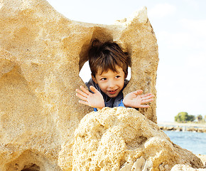 Image showing little cute boy on sea coast thumbs up playing with rocks