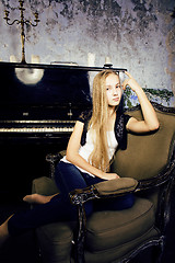 Image showing pretty young blond real girl at piano in old-style rusted interi