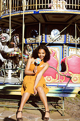 Image showing cool real teenage girl with candy near carousels at amusement pa