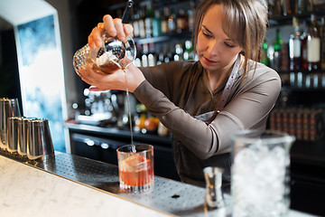 Image showing barmaid with glass and jug preparing cocktail