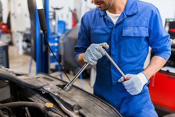 Image showing mechanic man with wrench repairing car at workshop