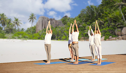 Image showing group of people making yoga exercises over beach