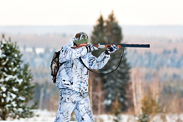 Image showing the hunter in winter camouflage shooting from a gun