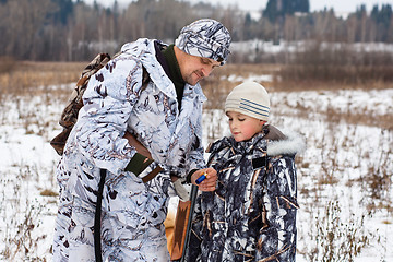 Image showing hunter shows his son how to charge the gun