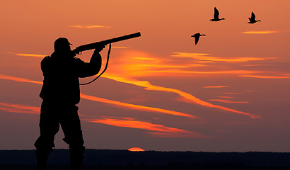 Image showing the silhouette of a hunter on sunset background