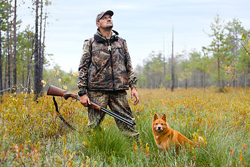 Image showing hunter with a gun and a dog on the swamp