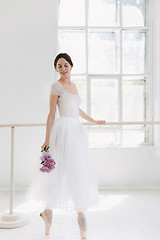 Image showing Young and incredibly beautiful ballerina is posing and dancing in a white studio