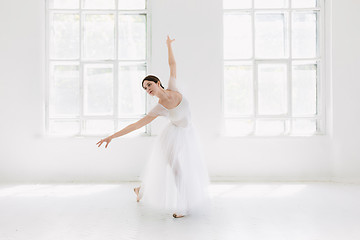 Image showing Young and incredibly beautiful ballerina is posing and dancing in a white studio