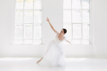 Image showing Young and incredibly beautiful ballerina is posing and dancing in a white studio