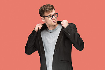 Image showing Young handsome man in black suit and glasses isolated on red background