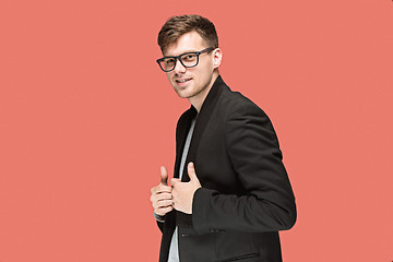 Image showing Young handsome man in black suit and glasses isolated on red background