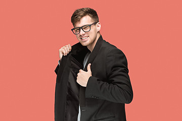 Image showing Young handsome man in black suit and glasses isolated on red background