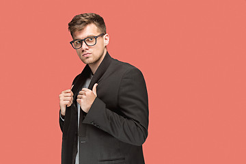 Image showing Young handsome man in black suit and glasses isolated on red background