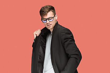 Image showing Young handsome man in black suit and glasses isolated on red background