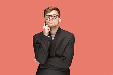 Image showing The young caucasian businessman on red background talking on cell phone