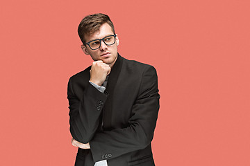 Image showing Young handsome man in black suit and glasses isolated on red background