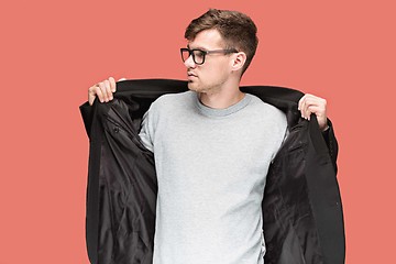 Image showing Young handsome man in black suit and glasses isolated on red background