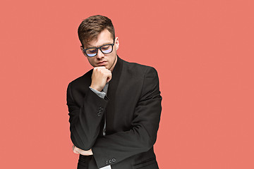 Image showing Young handsome man in black suit and glasses isolated on red background