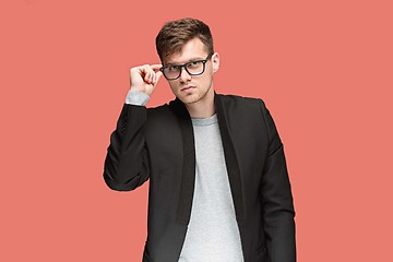 Image showing Young handsome man in black suit and glasses isolated on red background