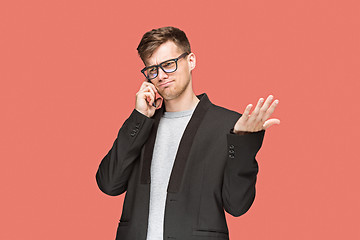 Image showing The young caucasian businessman on red background talking on cell phone