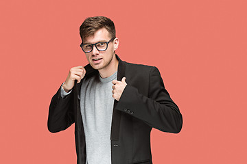 Image showing Young handsome man in black suit and glasses isolated on red background