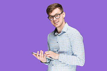 Image showing The young man in a shirt working on laptop on lilac backgroundin