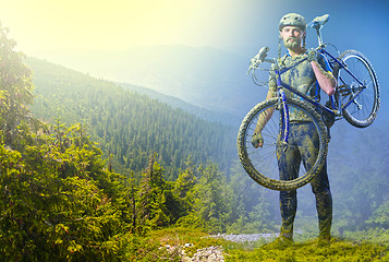 Image showing The man with bike in sand standing on mountains background. Collage
