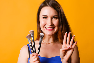 Image showing Smiling brunette with makeup brushes