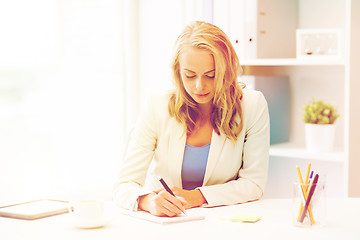 Image showing businesswoman writing to notebook at office