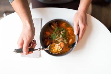 Image showing woman eating seafood soup at restaurant