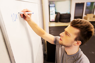 Image showing man writing numbers to whiteboard in gym