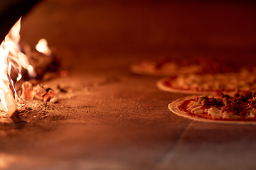 Image showing pizza baking in oven at pizzeria