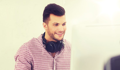 Image showing creative man with headphones and computer