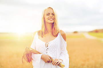 Image showing happy young woman with spikelets on cereal field