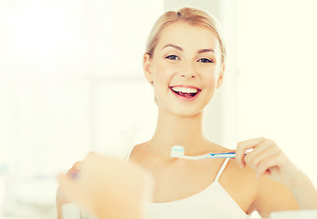 Image showing woman with toothbrush cleaning teeth at bathroom