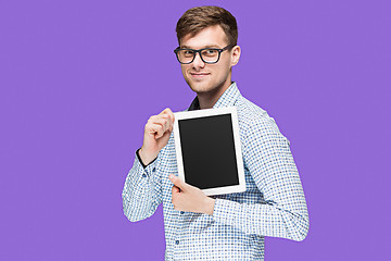 Image showing The young man in a shirt working on laptop on lilac backgroundin