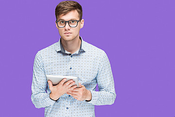 Image showing The young man in a shirt working on laptop on lilac backgroundin