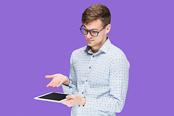 Image showing The young man in a shirt working on laptop on lilac backgroundin