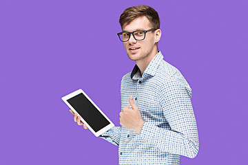 Image showing The young man in a shirt working on laptop on lilac backgroundin