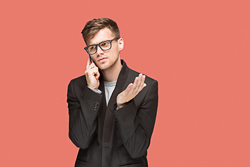 Image showing The young caucasian businessman on red background talking on cell phone